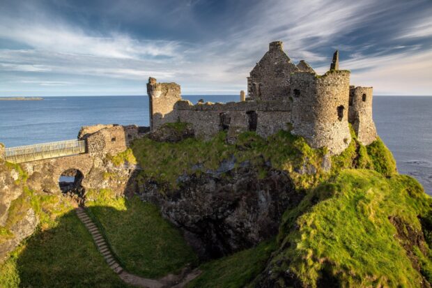 Ancient castle ruins on a green cliff overlooking the sea in Ireland