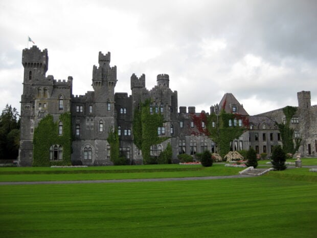 Historic stone Irish castle covered with green ivy and well kept lawn