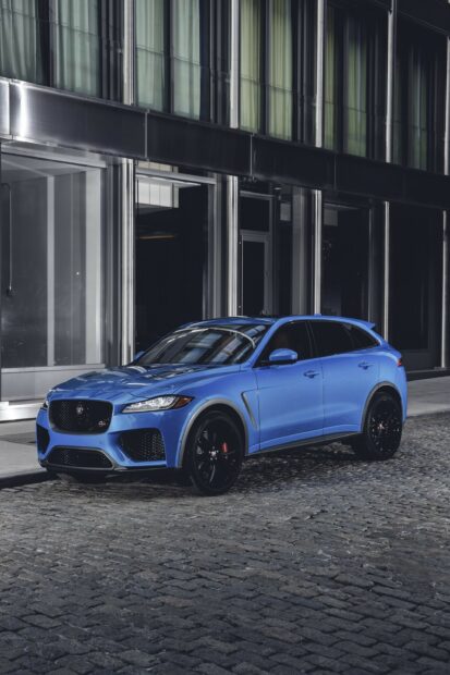 Blue Jaguar Cars parked on a cobblestone street in front of modern glass building