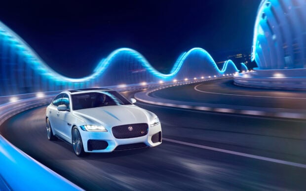 White Jaguar Cars driving fast on a futuristic illuminated bridge at night