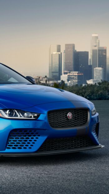 Front view of a blue Jaguar car parked with city skyline in the background