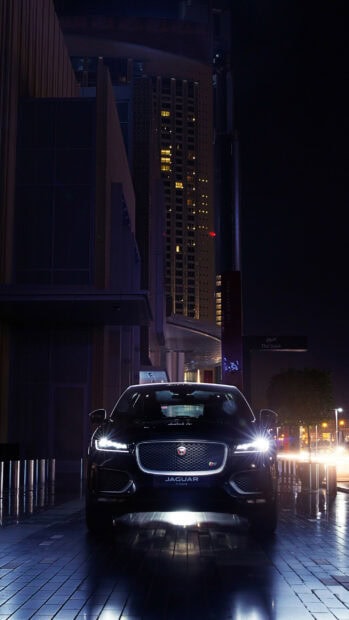 Jaguar car parked at night in an urban area with illuminated buildings in the background