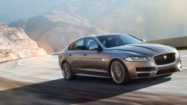 A sleek Jaguar cars driving fast on a winding mountain road in high resolution