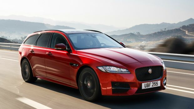 Red Jaguar Cars driving on a highway with mountain background