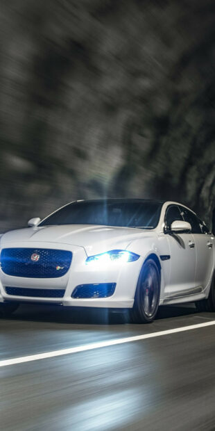 White Jaguar Cars driving fast on a road at night with bright headlights