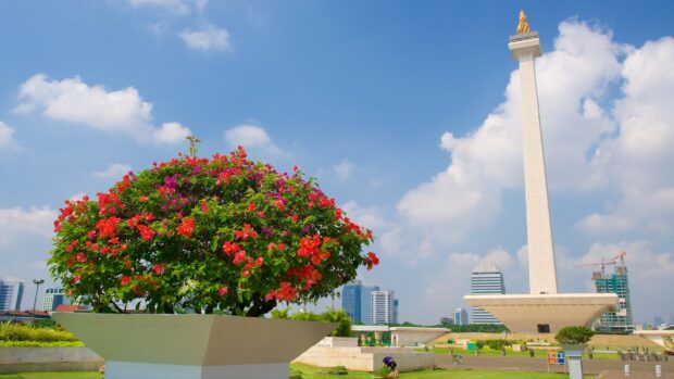 A vibrant flower bush near the iconic Jakarta National Monument in the cityscape of Jakarta