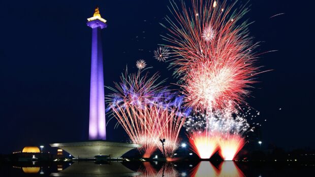 Nighttime fireworks display near National Monument in Jakarta with vibrant colors