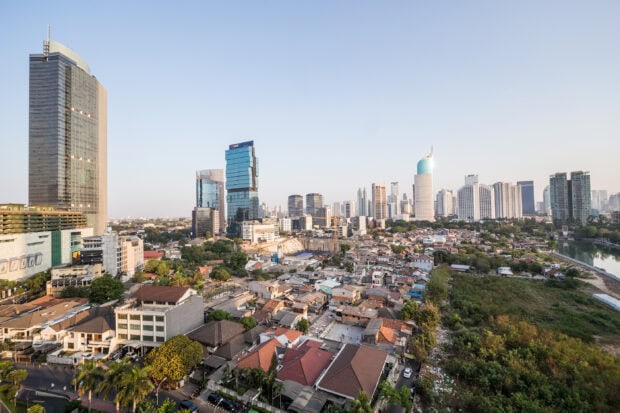 A panoramic view of Jakarta cityscape with modern skyscrapers and residential areas in the afternoon light