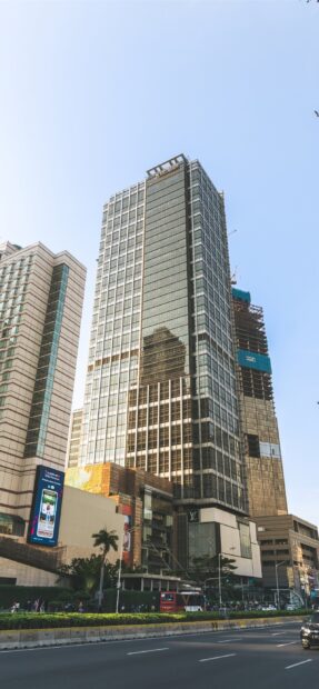 Modern skyscraper in Jakarta city center with clear blue sky and busy street view