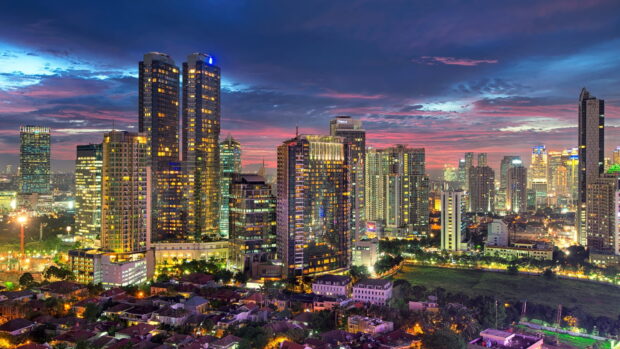 The vibrant cityscape of Jakarta at dusk with illuminated skyscrapers and dramatic skies