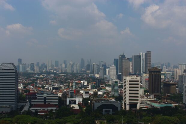 Jakarta cityscape with modern buildings and greenery under a cloudy sky in Jakarta