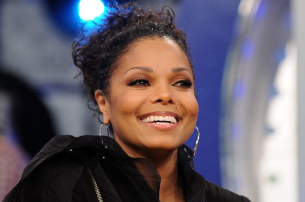 Close up of Janet Jackson smiling with hoop earrings and curly hair updo