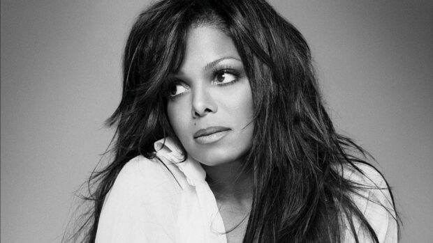 Janet Jackson looking thoughtfully to the side with long hair in a black and white portrait