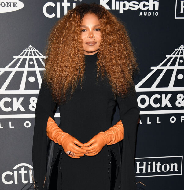 Janet Jackson wearing black dress and orange gloves at an event