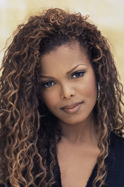 Janet Jackson with curly hair looking at the camera in a close up portrait