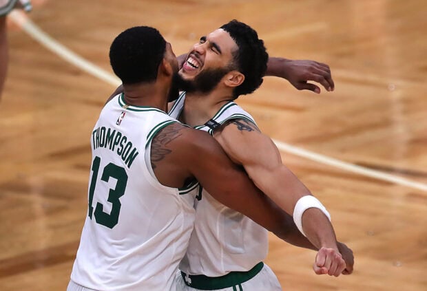 Jayson Tatum celebrates with teammate on basketball court after scoring a point