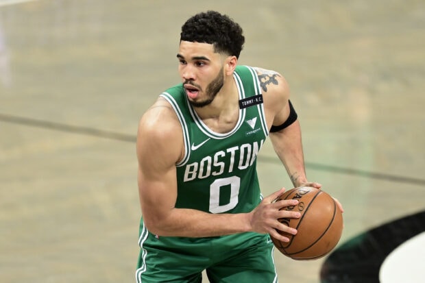 Jayson Tatum wearing a Boston basketball jersey holding a basketball during a game