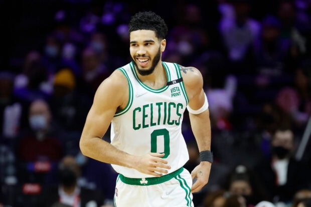 Jayson Tatum wearing a Celtics basketball uniform smiling on the court during a game