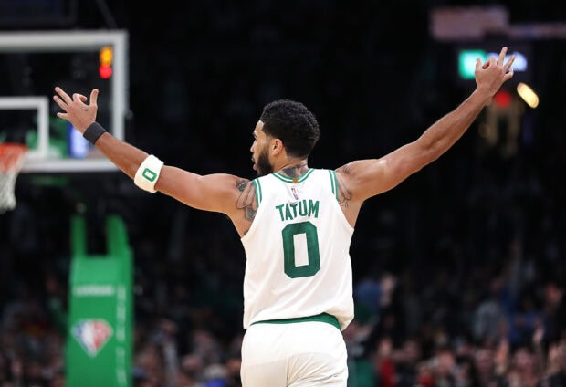 Jayson Tatum celebrating on the basketball court with arms raised and visible tattoos