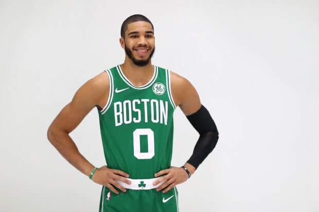 Jayson Tatum in a Boston basketball uniform smiling with hands on hips