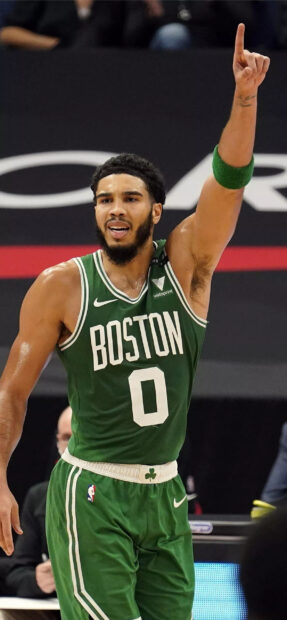 Jayson Tatum wearing a Boston basketball jersey raising his hand during a game