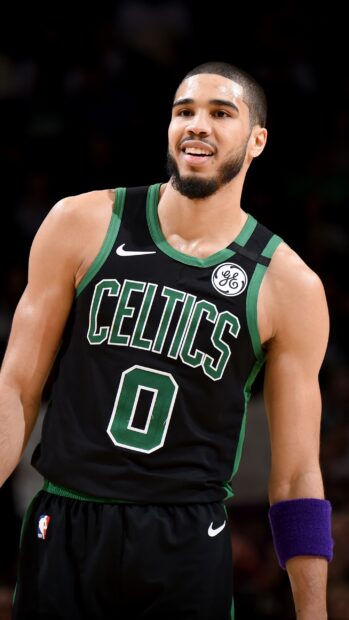 Jayson Tatum wearing a Celtics jersey during a basketball game and smiling confidently