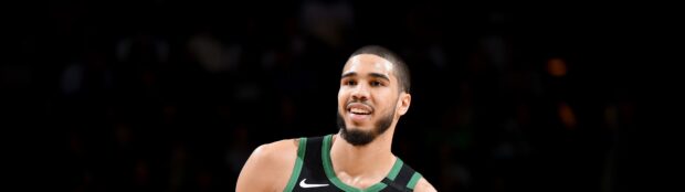 Jayson Tatum smiling during a basketball game wearing a Boston Celtics jersey