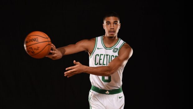 Jayson Tatum in Celtics jersey passing a basketball during a game action