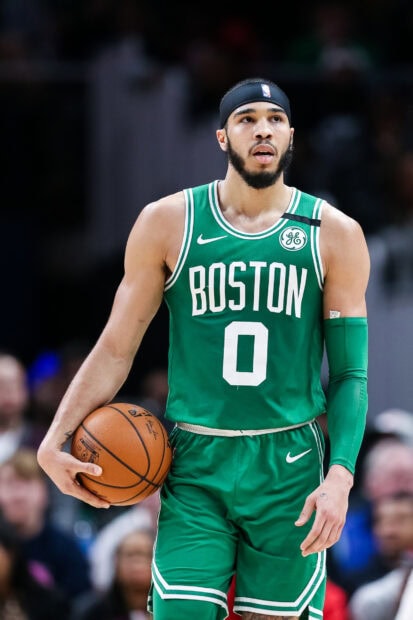 Jayson Tatum holding a basketball wearing a Boston Celtics jersey during a game