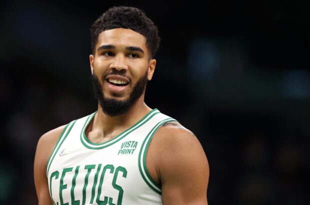 Jayson Tatum smiling in a Celtics basketball jersey during a game