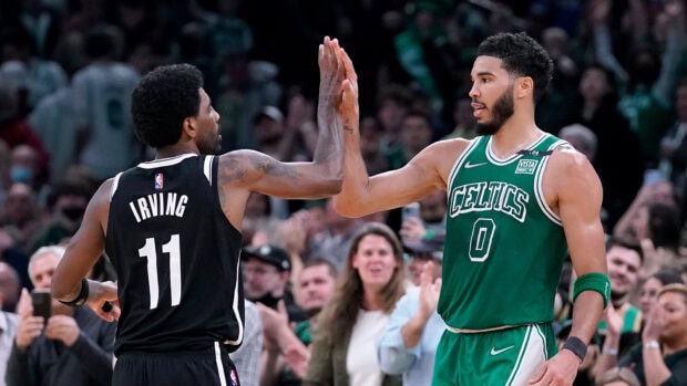 Jayson Tatum celebrating with a basketball player in a Celtics uniform during a game
