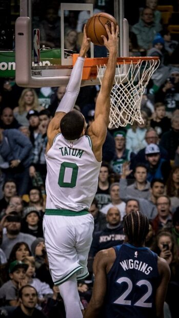 Jayson Tatum jumping to dunk the basketball during an intense game