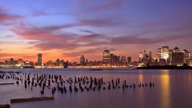 The beautiful Jersey City skyline at sunset with calm water and colorful sky