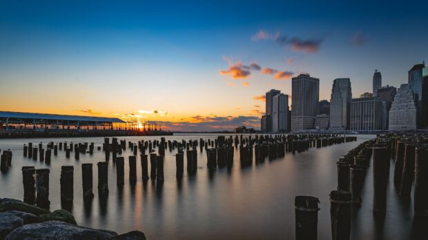 Sunset over Jersey City skyline with old pier posts in calm water