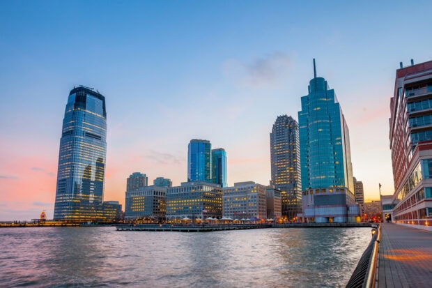Jersey City skyline with high rise buildings reflecting at sunset over the water