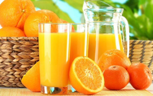 Fresh citrus fruits and a sliced orange with two glasses of juice and a pitcher on the table