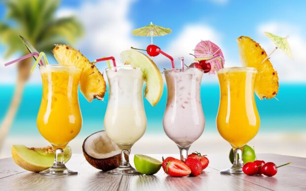Tropical juice arrangement with pineapple melon coconut and cherry on summer beach