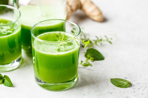 Fresh green juice with herbs and roots on the table