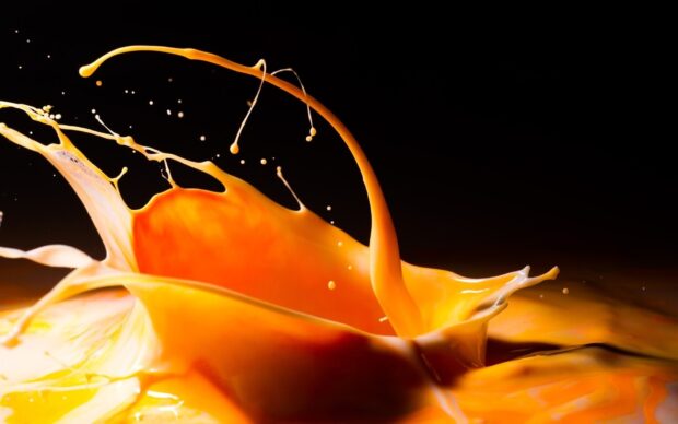 Orange juice splash captured in motion on black background