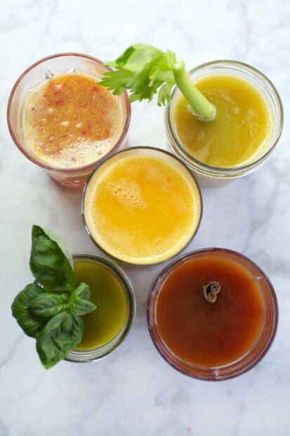 Fresh juice with basil and celery garnish on a white surface