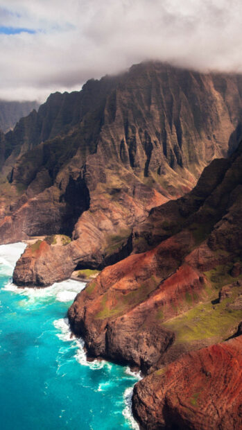 Dramatic cliffs and turquoise water along Kauai coast illuminated by sunlight