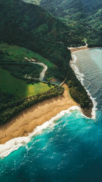 Aerial view of Kauai river flowing through lush green landscape to the beach