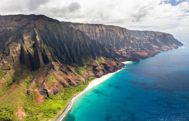 A scenic view of Kauai coastline with rugged cliffs and turquoise ocean water