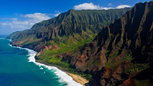 Dramatic Kauai cliffs with lush greenery meeting the turquoise ocean coast in bright sunlight
