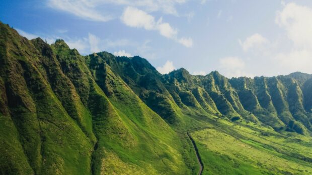 Lush Kauai mountain ridges covered in green vegetation under a blue sky