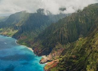 Aerial view of Kauai coastline with lush cliffs and clear blue ocean
