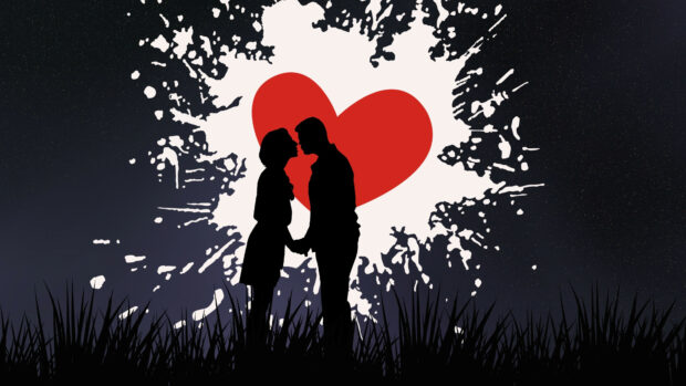 A couple silhouette shares a kiss in front of a large red heart shape on a dark night sky background