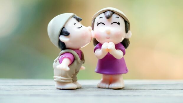 A kiss figurine showing a boy giving a kiss to a girl figurine with closed eyes and joyful expression