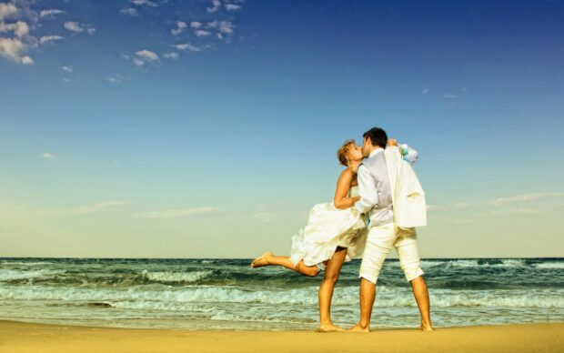 A couple sharing a romantic kiss on the beach at sunset with a beautiful ocean view