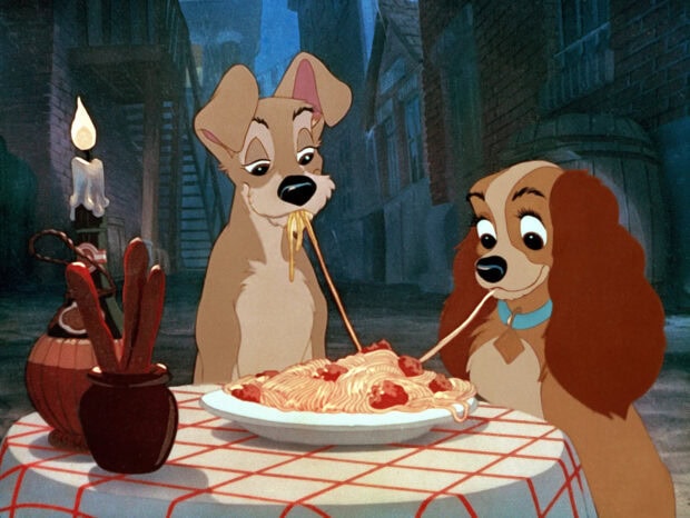 The Lady and the Tramp cartoon characters sharing a spaghetti dinner in an alley scene